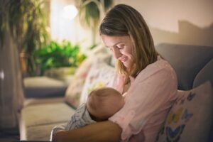 A woman holding her baby in the arms of another person.