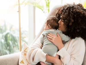 A woman holding her baby in the arms of another person.