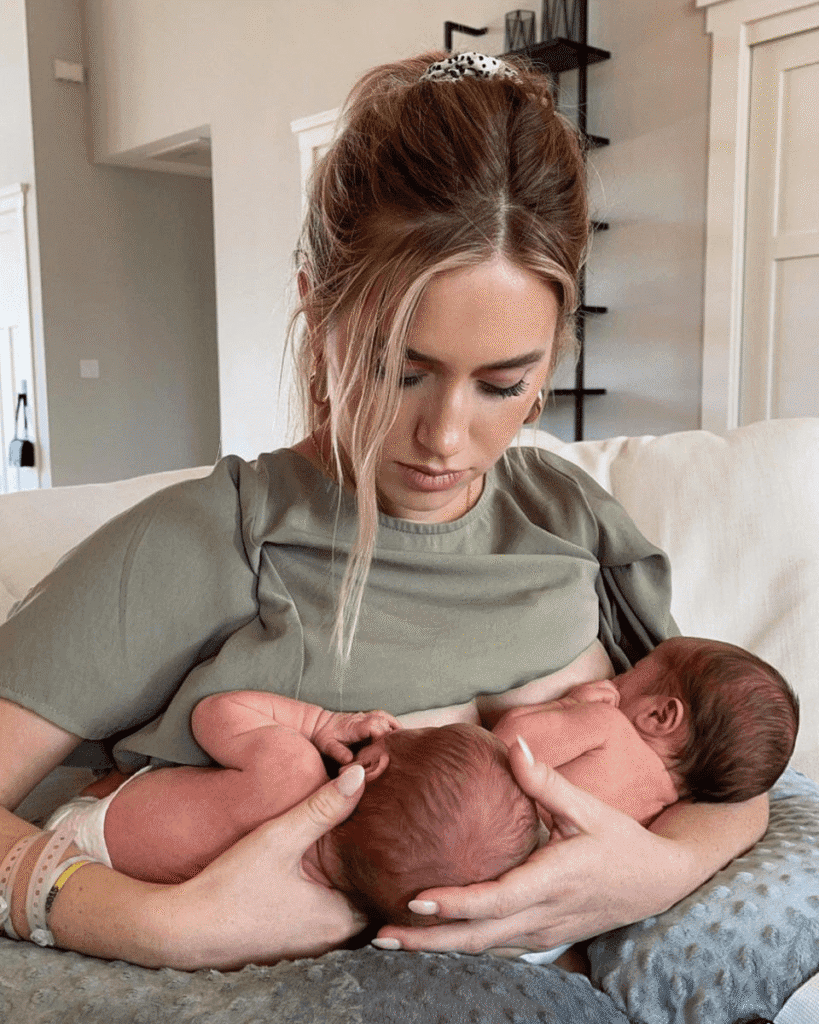 Mother breastfeeding newborn twins on couch.